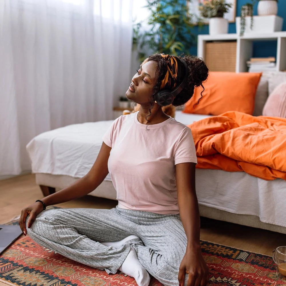A woman with closed eyes and a calm expression doing a brief body-scan practice in a quiet room